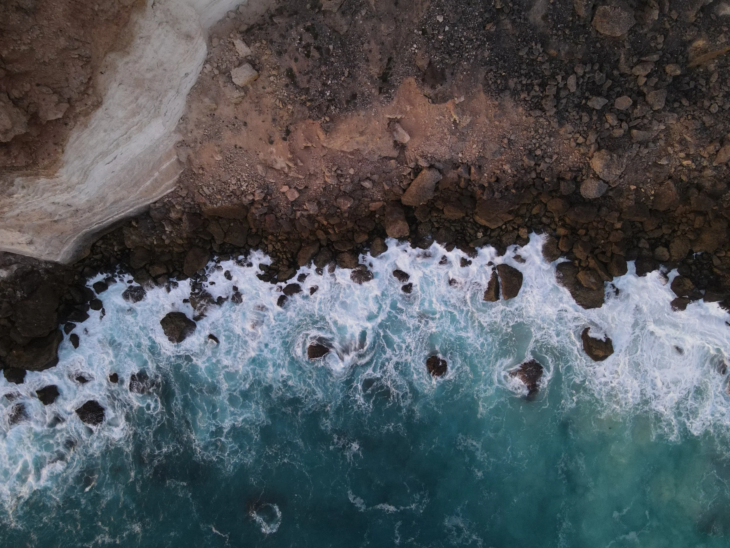 Aerial view of a rocky coastline with waves crashing against the rocks.