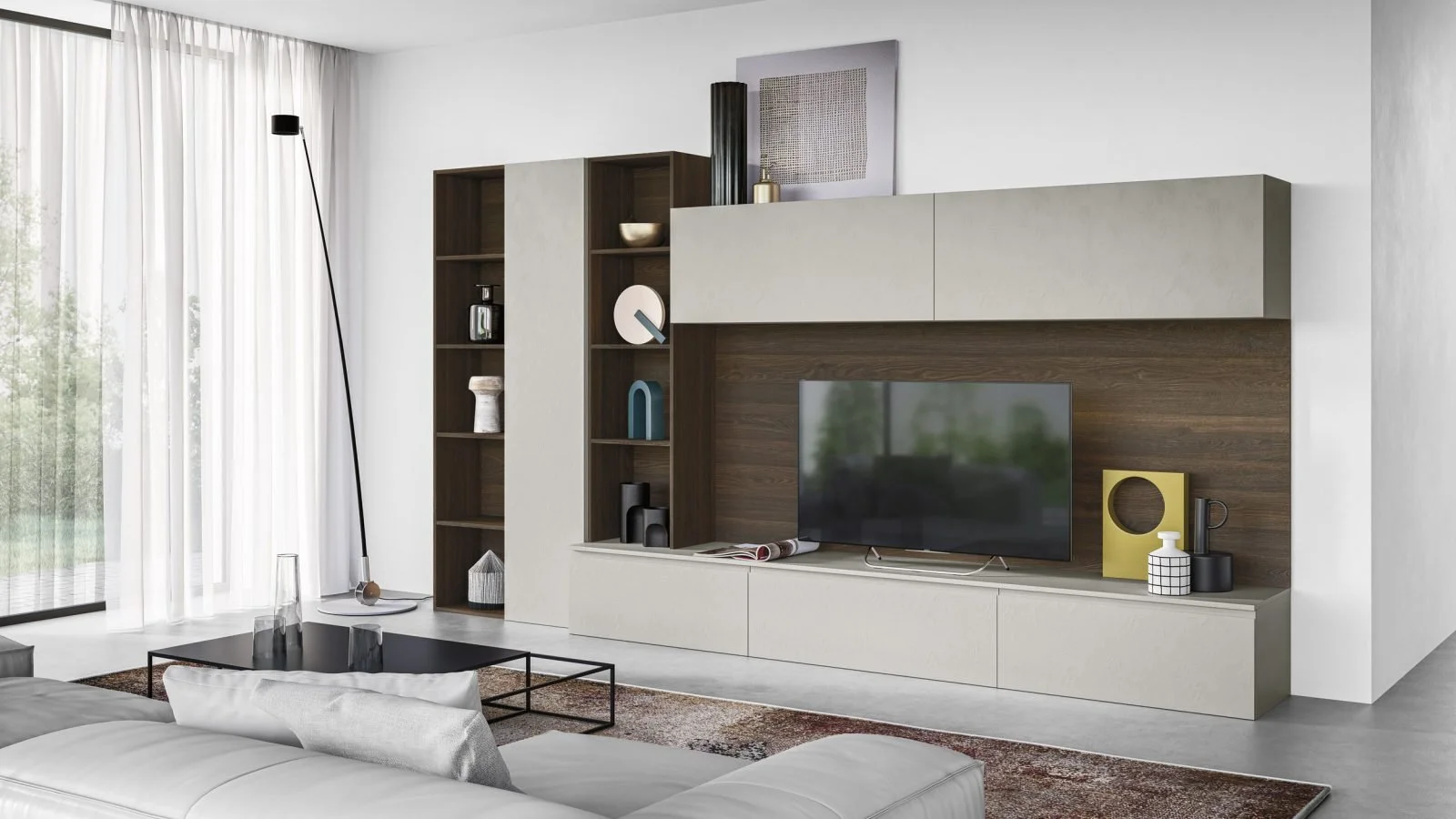 Modern living room with a white sofa, a black coffee table with glass vases, a tall black floor lamp, and a large window with white curtains. The wall features a built-in modular entertainment unit with a flat-screen TV, decorative objects, and shelv
