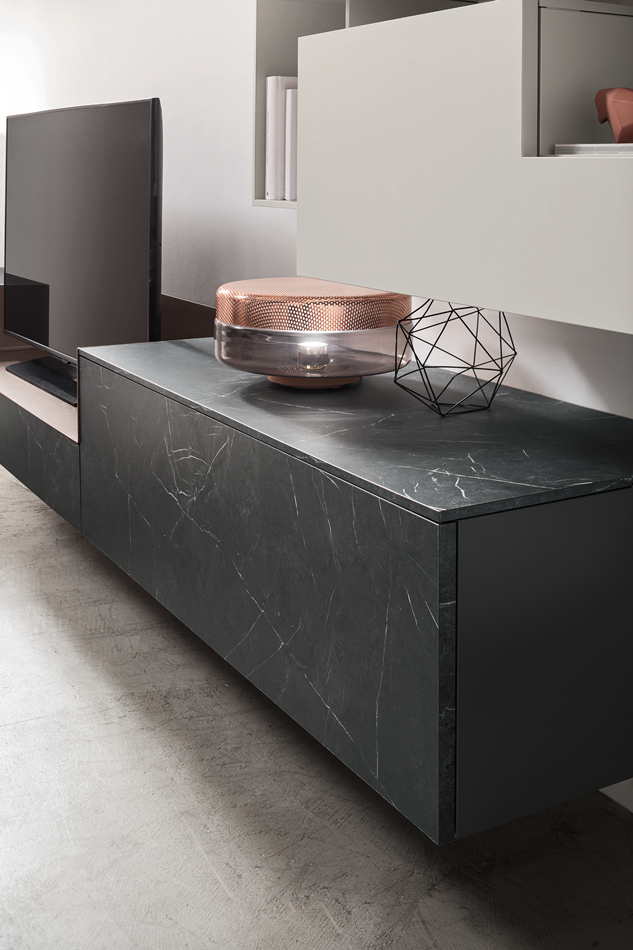 A modern living room with a black marble TV stand, decorated with a pink and clear glass decorative object and a black wire geometric sculpture.
