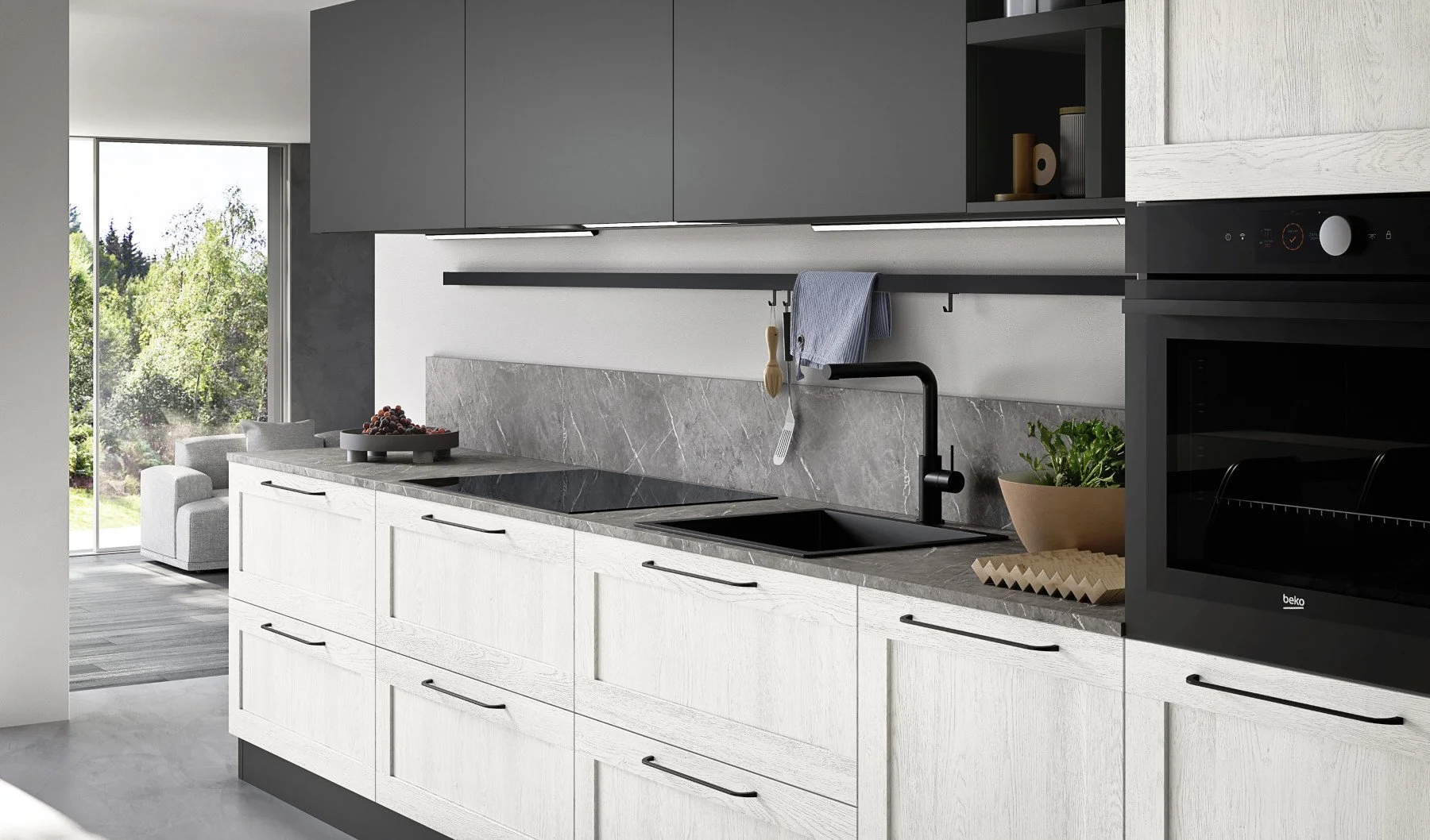 Modern kitchen with white cabinets, dark gray upper cabinets, marble backsplash, black sink and faucet, and a built-in oven. A bowl of fruit and a potted plant on the counter, with a view of a living area and garden outside.