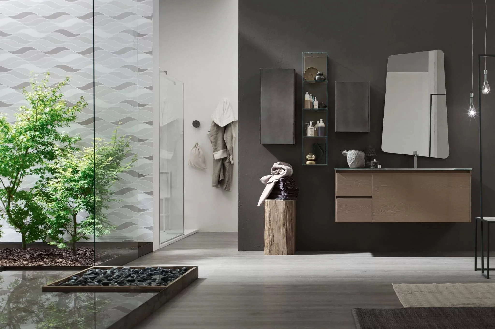 Modern bathroom with dark and white walls, wooden vanity with mirror, glass shower with patterned wall, indoor garden with green plants, wooden stool with rolled towels, hanging robes, and contemporary decor.