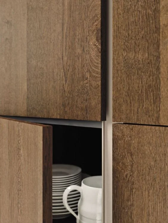 Close-up of a kitchen cabinet with an open door revealing stacked white plates and a white mug inside.