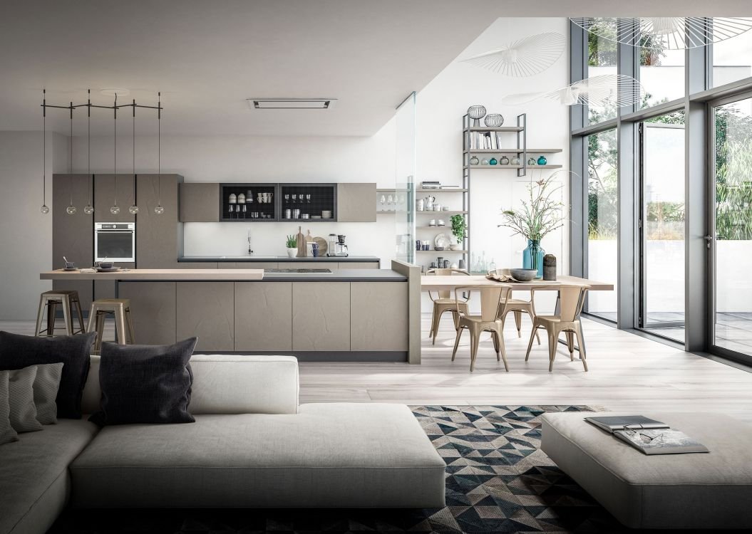 Modern, minimalist open-concept kitchen and living room with large windows, light-colored furniture, and decorative shelving with plants and art.