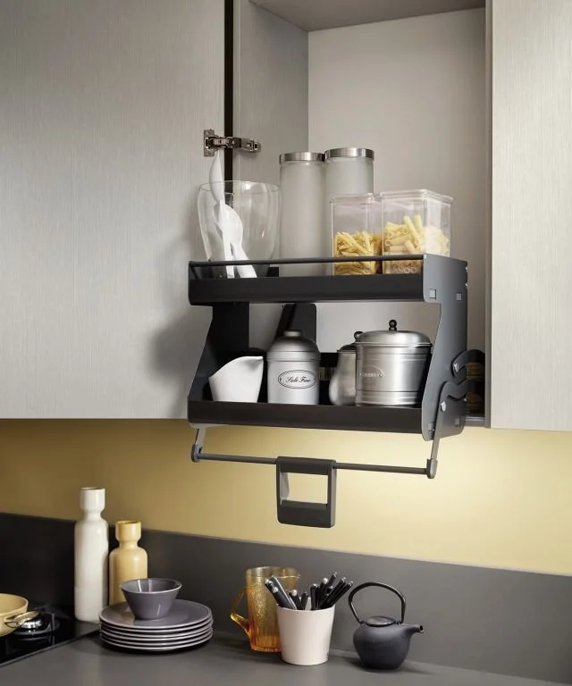Kitchen cabinet with storage shelf holding glass jars and containers, with plates and utensils on the counter below.