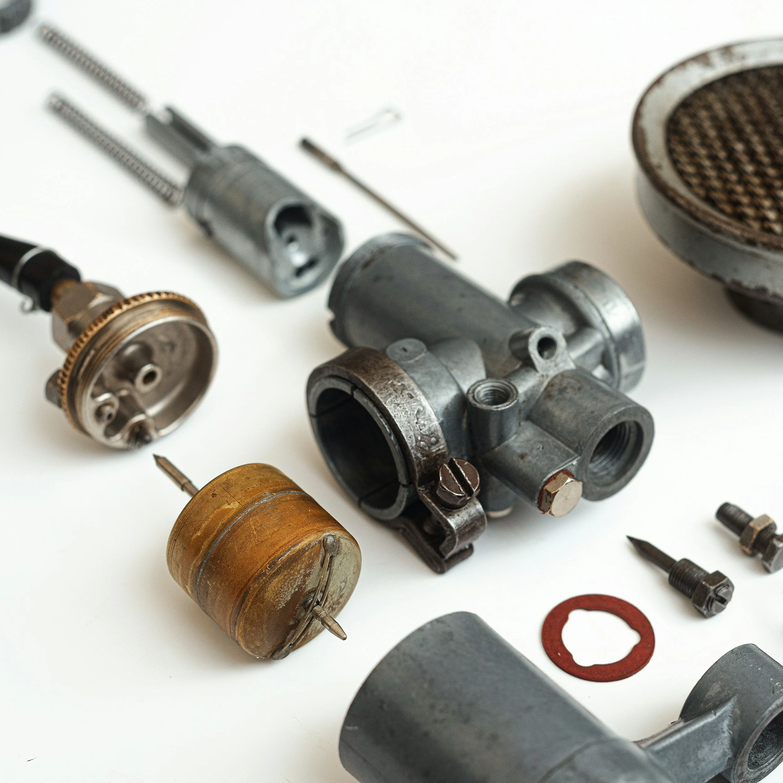 Disassembled automotive carburetor parts and components laid out on a white surface.