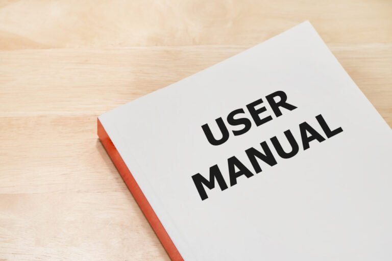 A user manual with a white cover and bold black text on a light wooden surface.