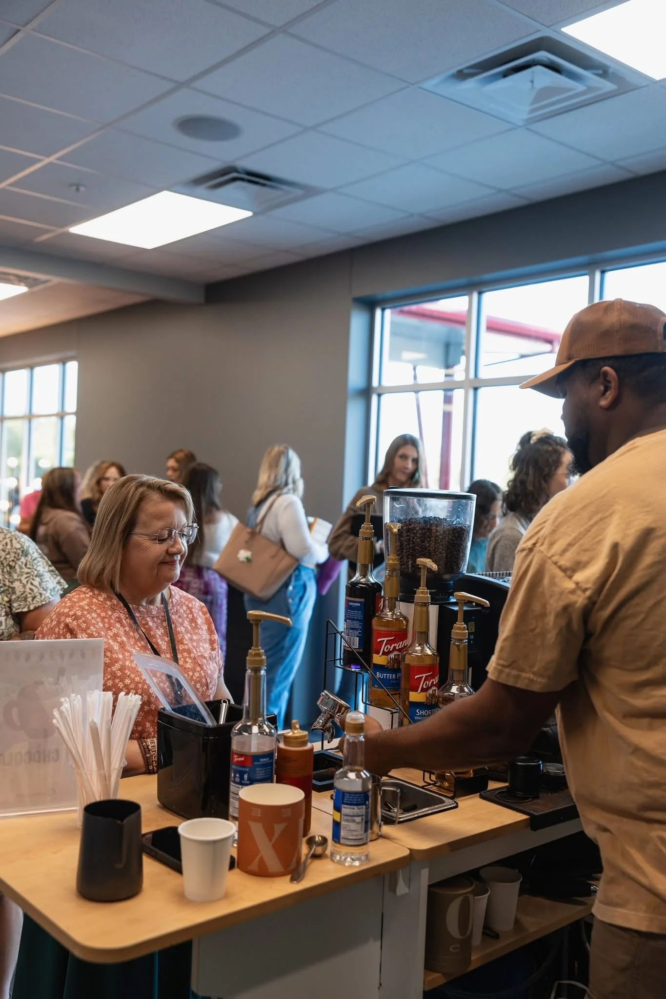 A glass measuring cup with coffee, sitting on a ridged black surface.
