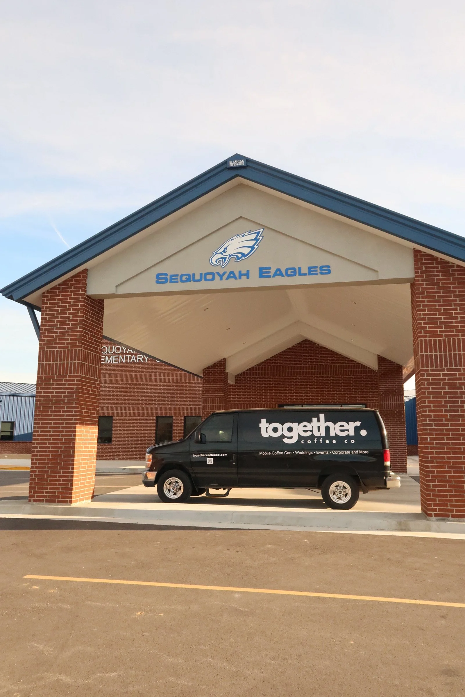 A glass measuring cup with coffee, sitting on a ridged black surface.