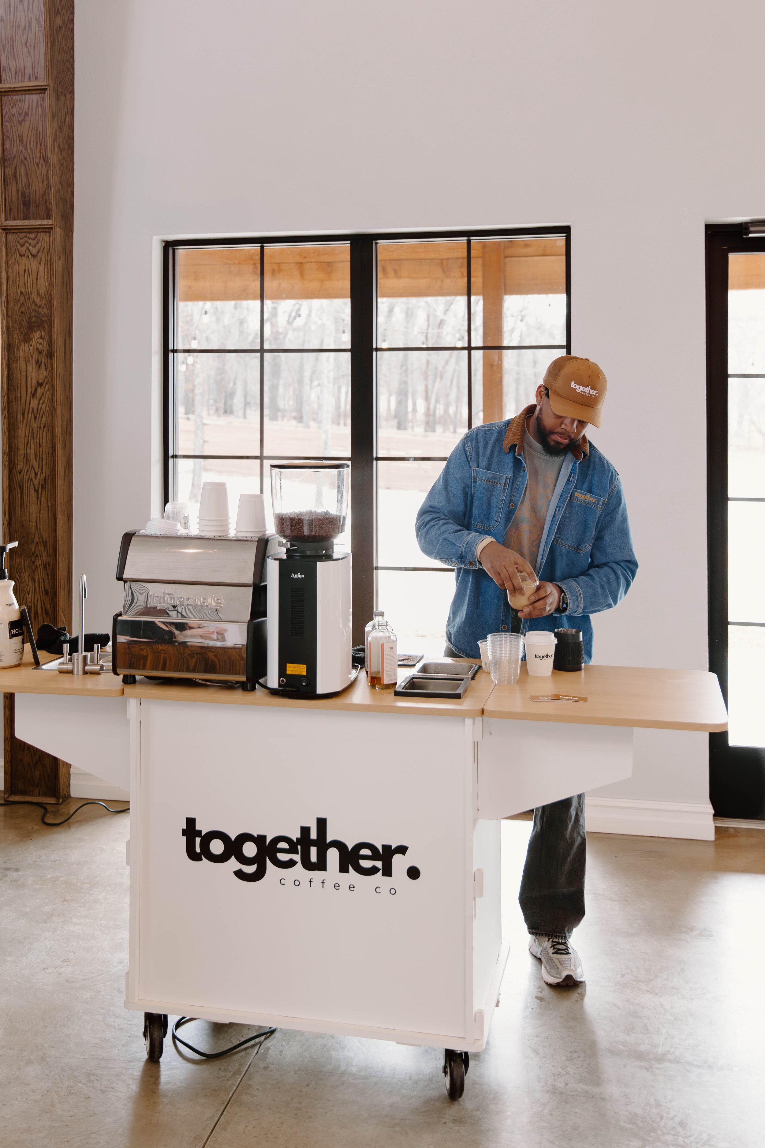 A hand holding a white cup of coffee with latte art on top.