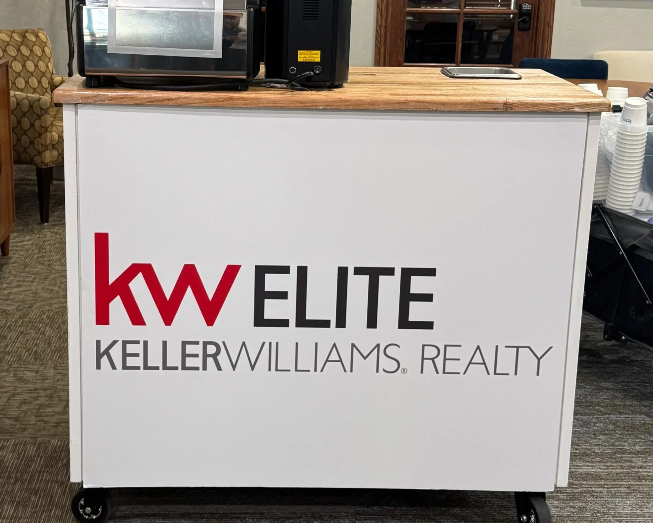 A hand holding a white cup of coffee with latte art on top.