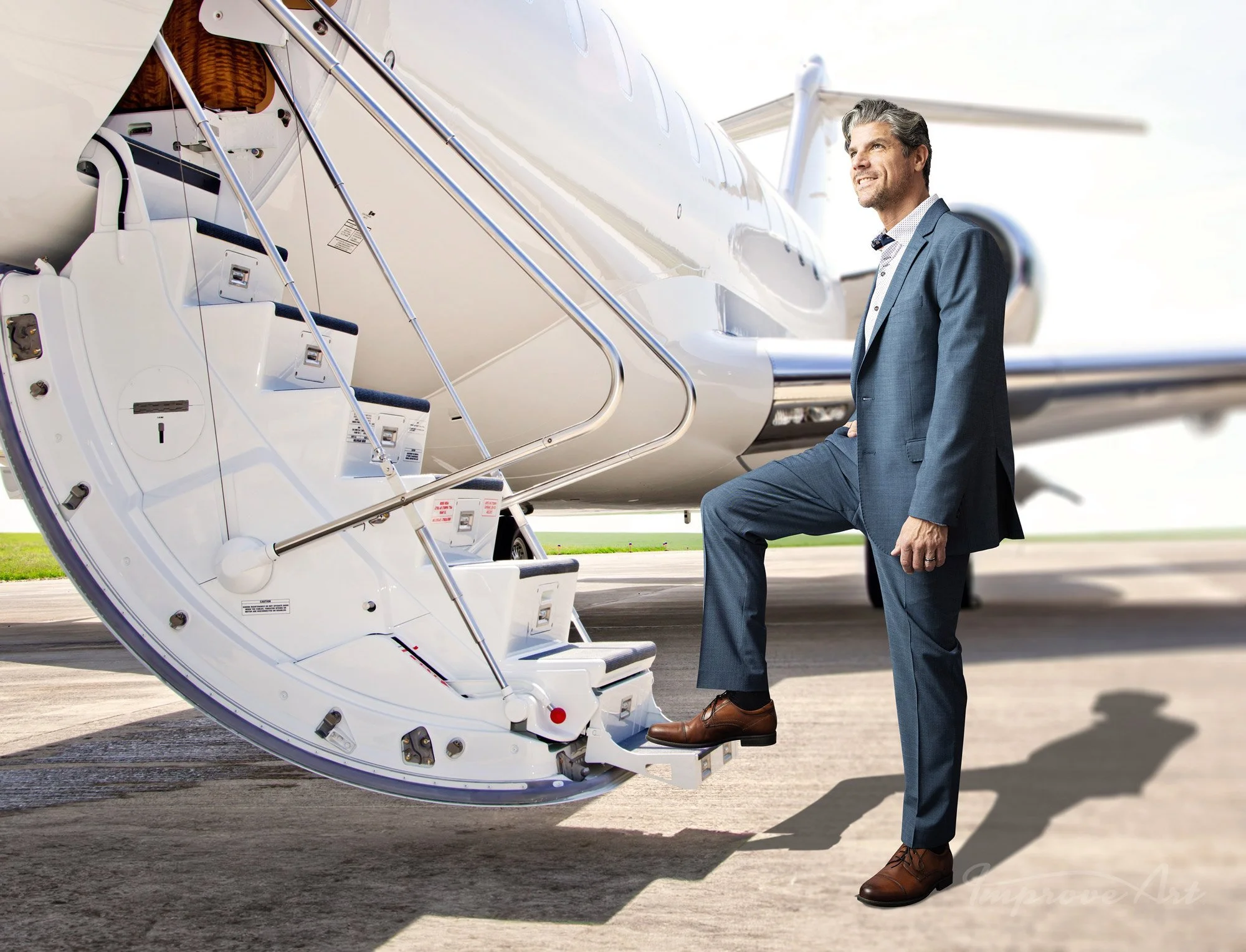 A man in a business suit with gray hair and beard, standing on an airport tarmac with one foot on the stairs of a private jet, smiling as he looks into the distance.
