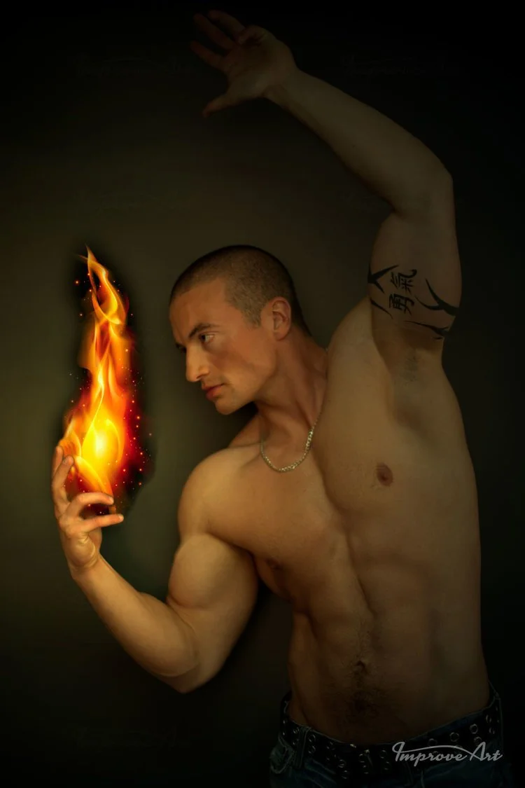 A shirtless man with a muscular build and a tattoo on his arm poses with one hand raised and the other hand holding a fiery flame against a dark background.
