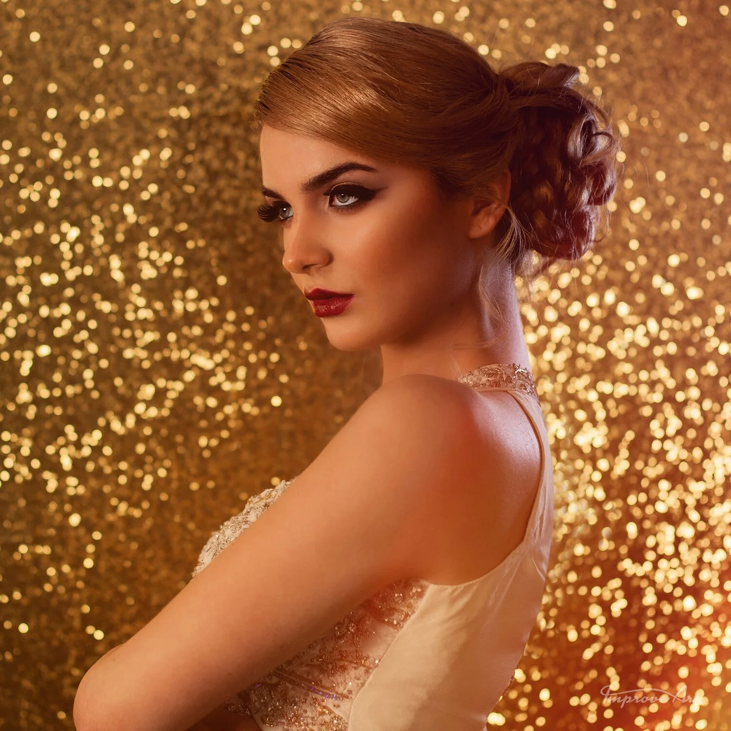 A woman with styled hair and makeup poses against a glittery gold background.