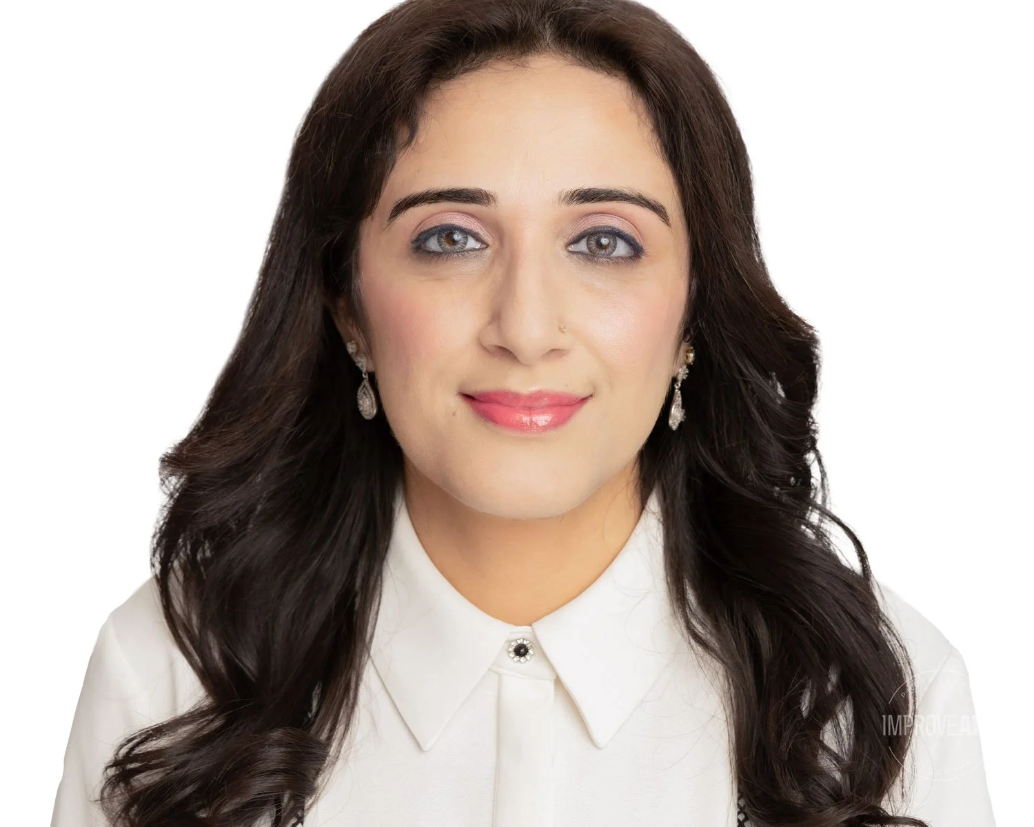A woman with long, dark hair wearing a white top and earrings, smiling at the camera against a white background.