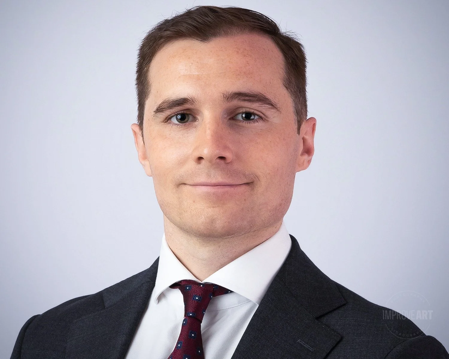 Headshot of a young man in a suit and tie against a plain background.