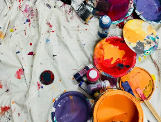 Paint palette with various colors and spilled paint on a cloth surface.
