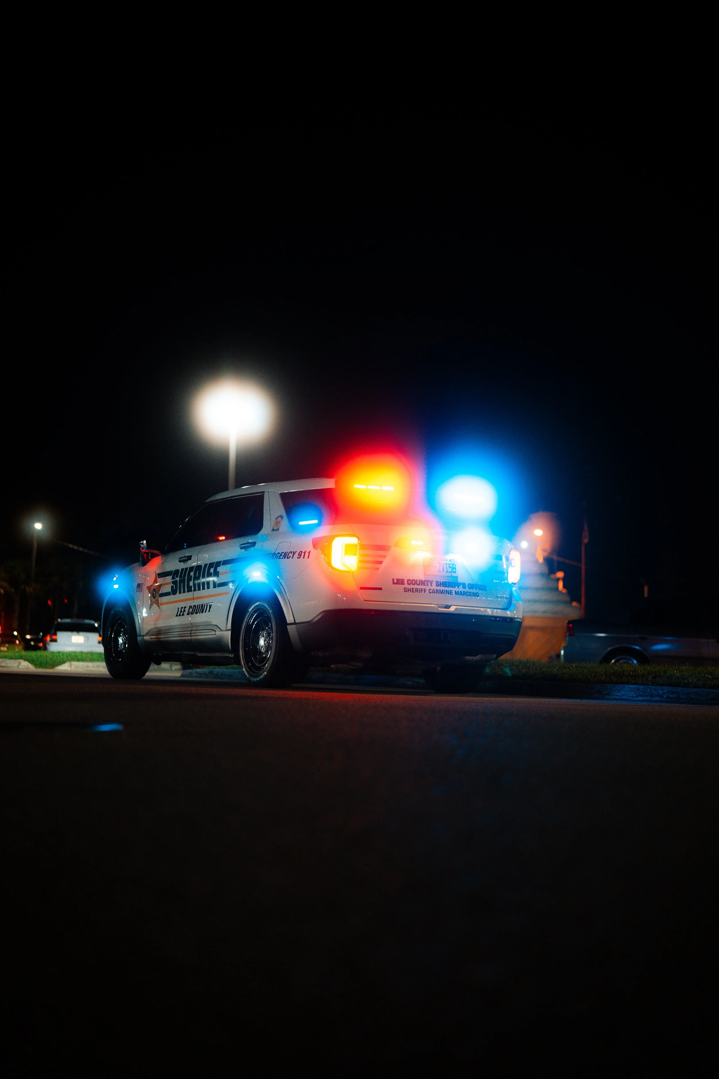 A Lee County sheriff's patrol car with red and blue emergency lights flashing at night.