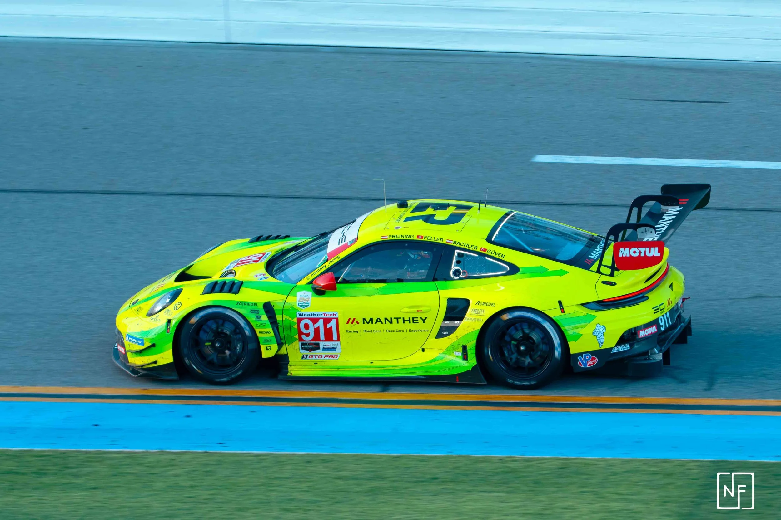 A bright yellow race car with the number 911 driving on a race track.