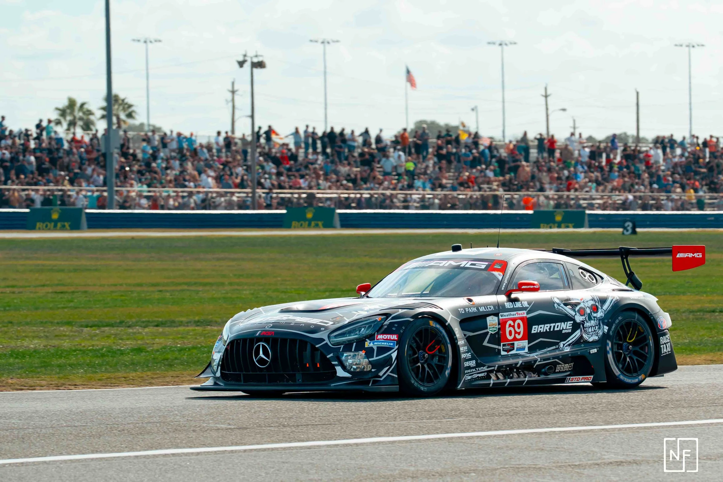 A race car on a track with a crowd of spectators in the background.