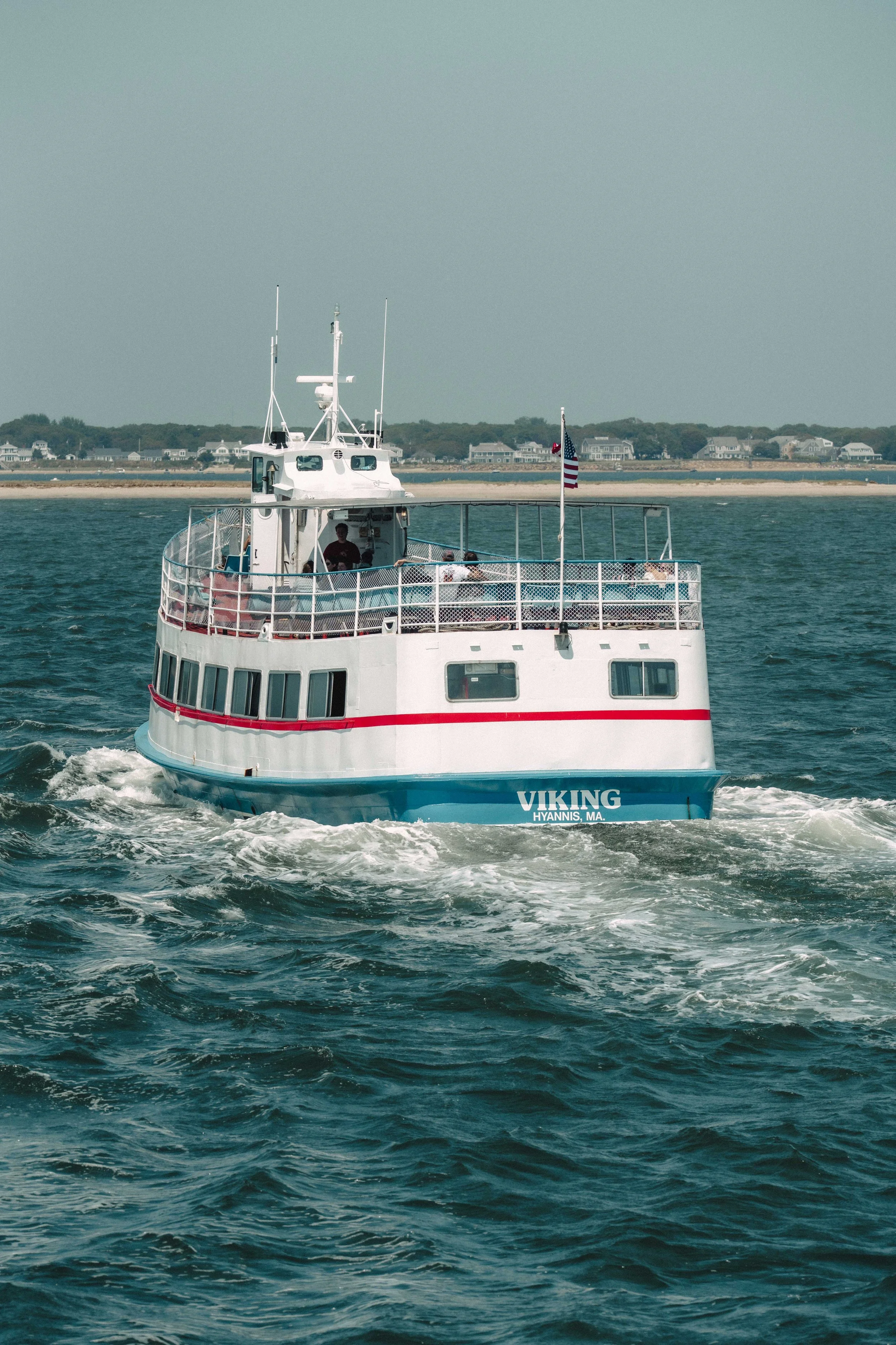 A white boat named Viking with blue and red accents on the water near the shoreline, with houses visible in the background.