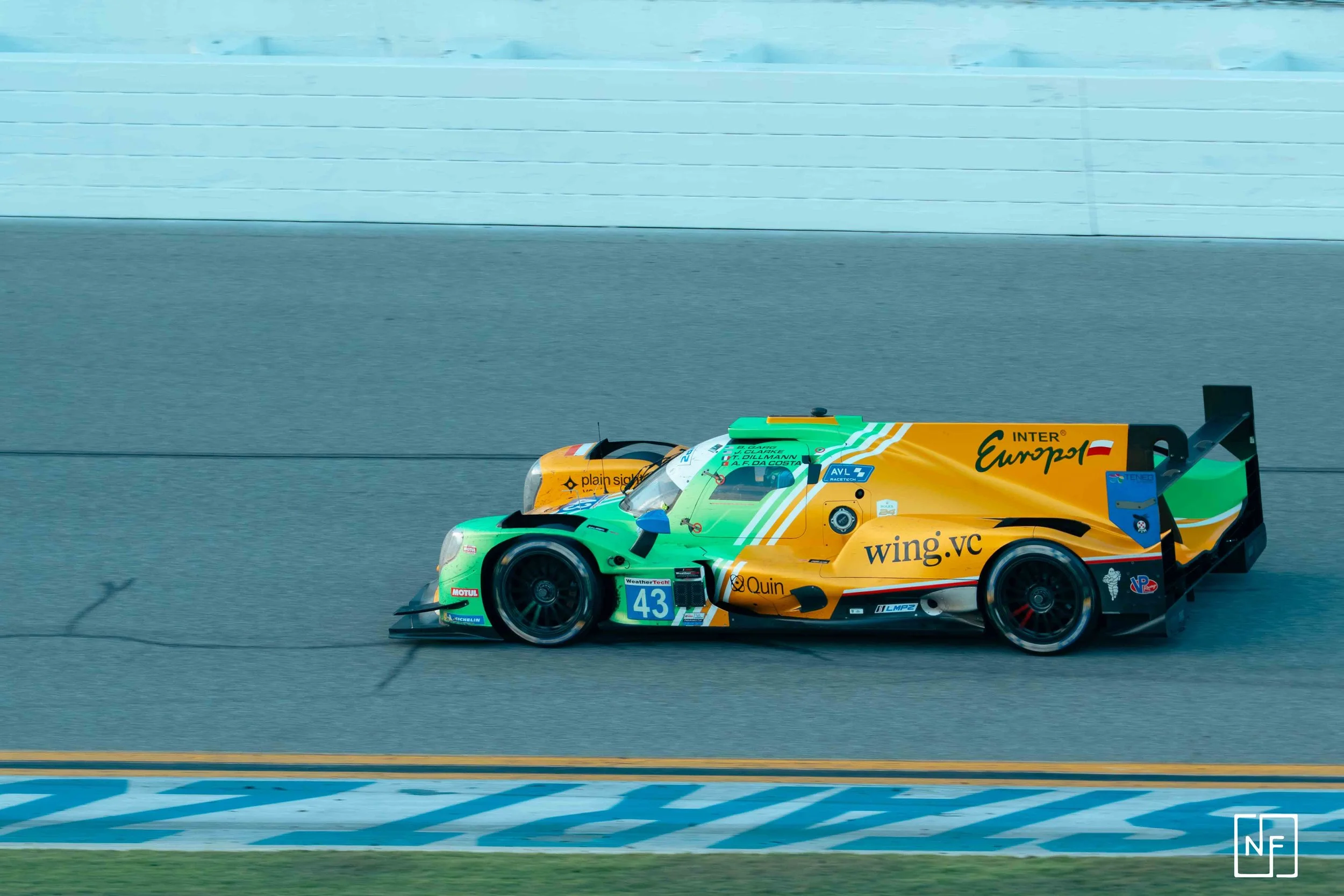 A race car with green, yellow, and black livery on a racetrack.