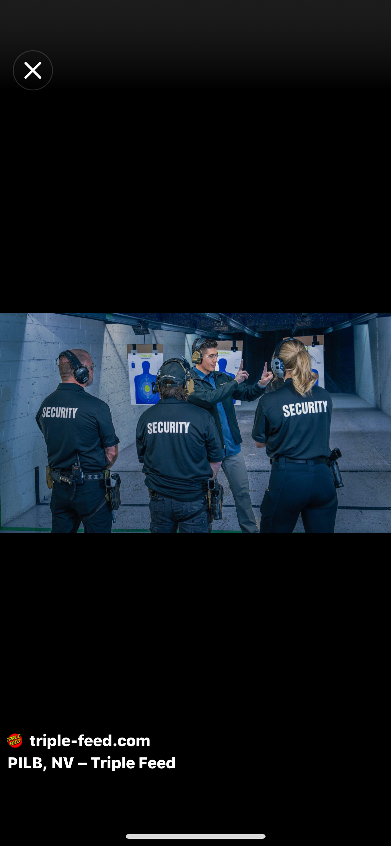 A group of security personnel in black uniforms with 'SECURITY' written on the back, standing in a shooting range with targets, listening to a man explaining shooting techniques.