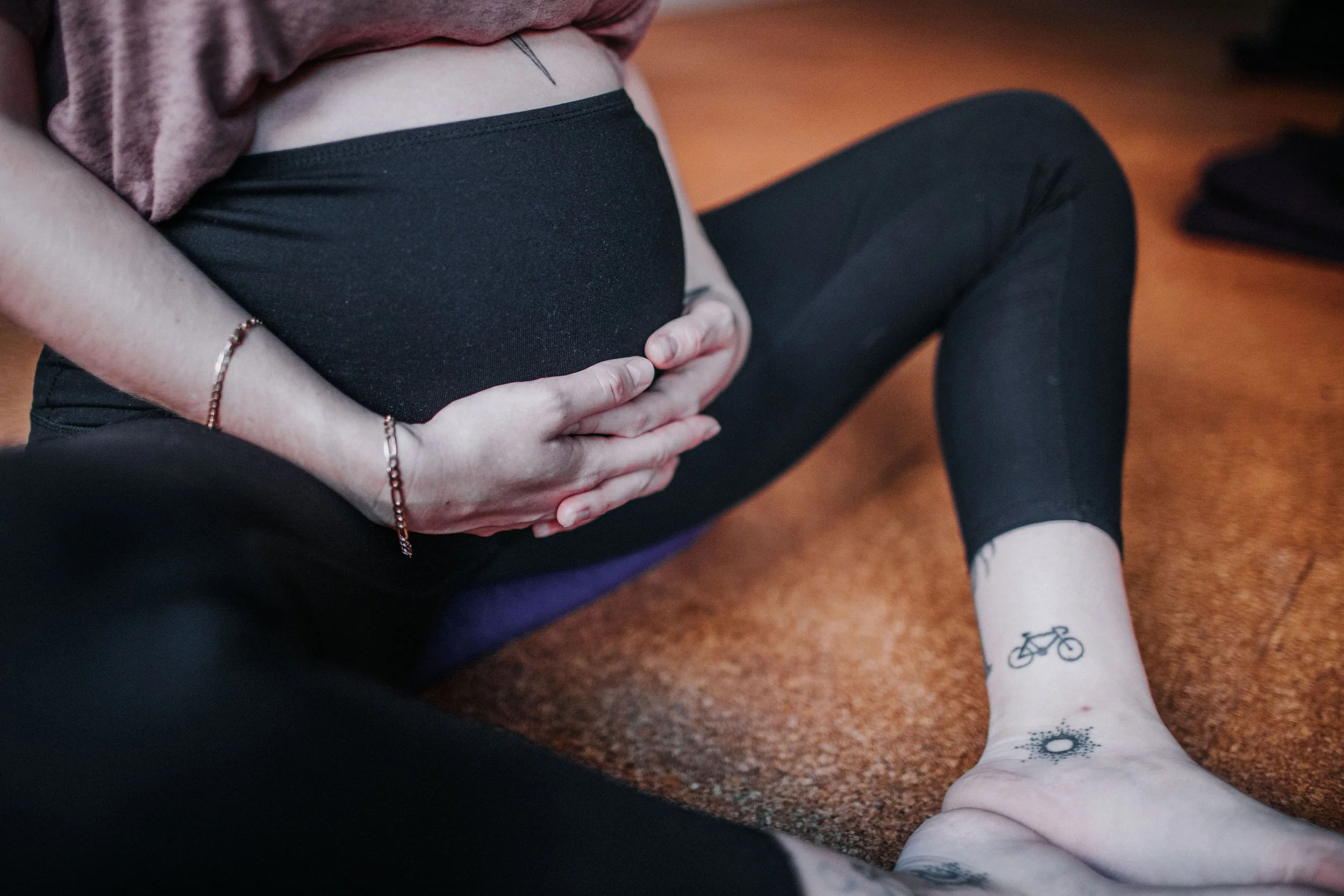 Pregnant woman holding her pregnant belly with hands in a prenatal yoga pose during meditation in a pregnancy yoga class in Perth