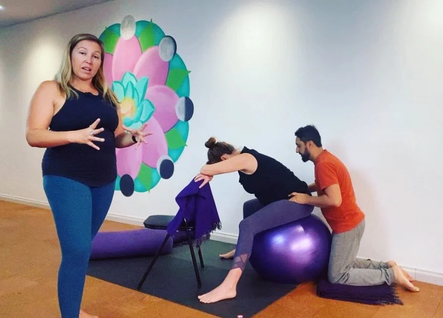 An expectant couple practicing yoga postures in an Active Birth workshop in preparation for labour.