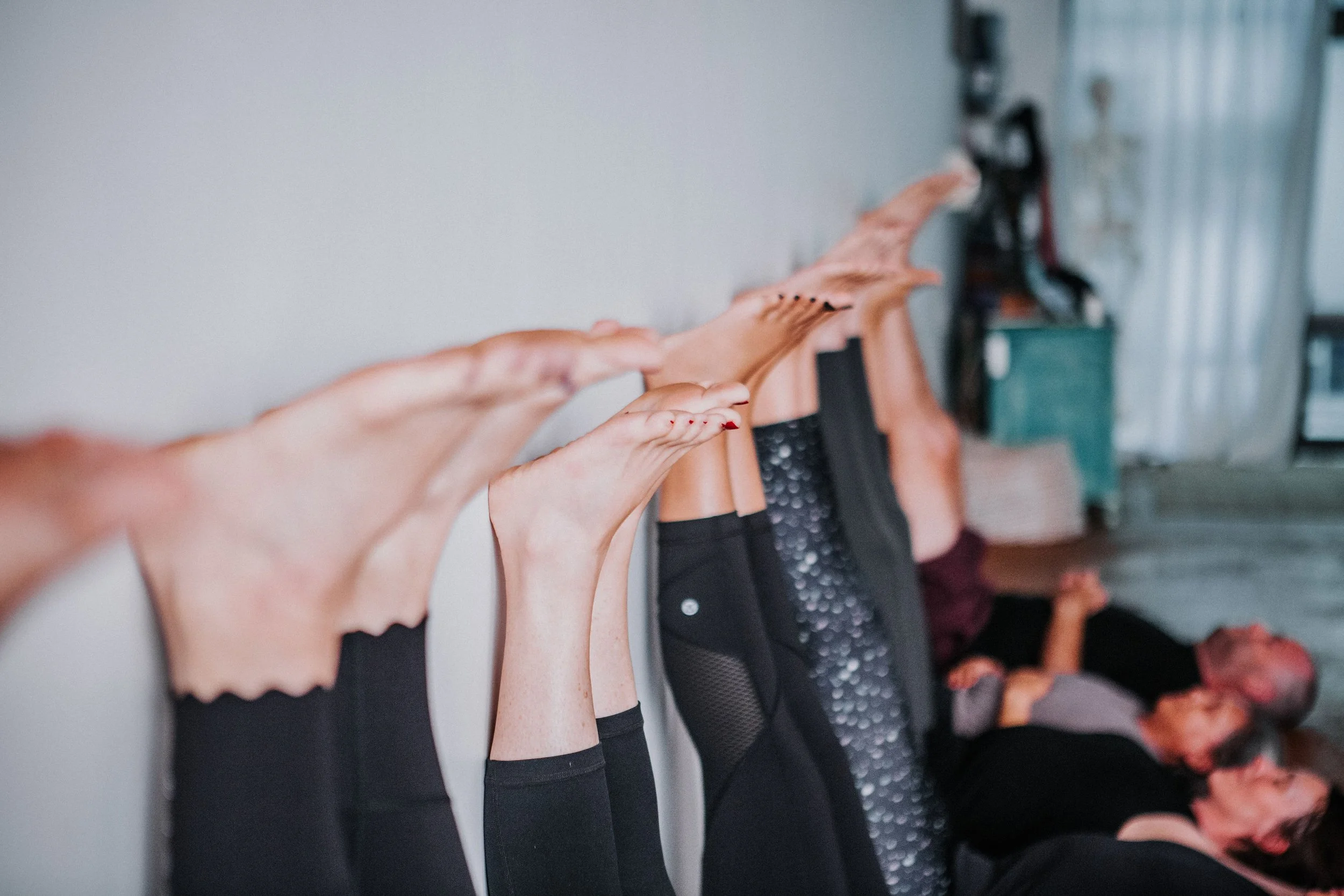 yoga class practicing a restorative legs up the wall pose