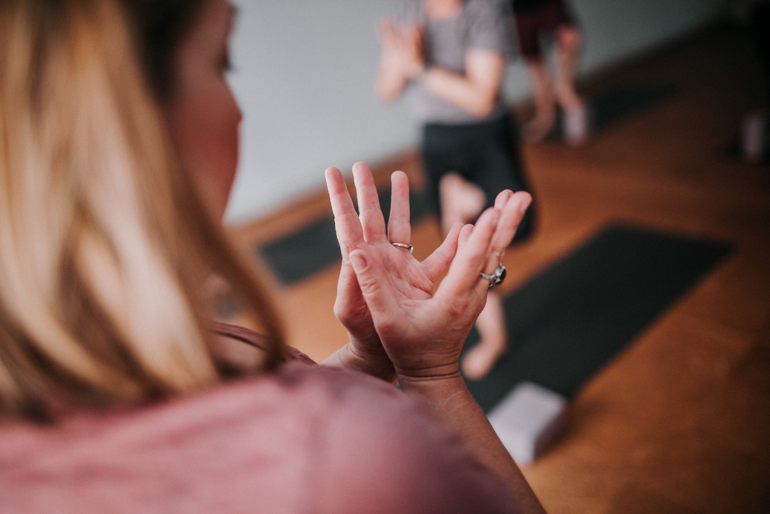 Close-up of padma mudra during a women's yoga class, with a person in the background in a Perth yoga studio, Bloom Yoga.