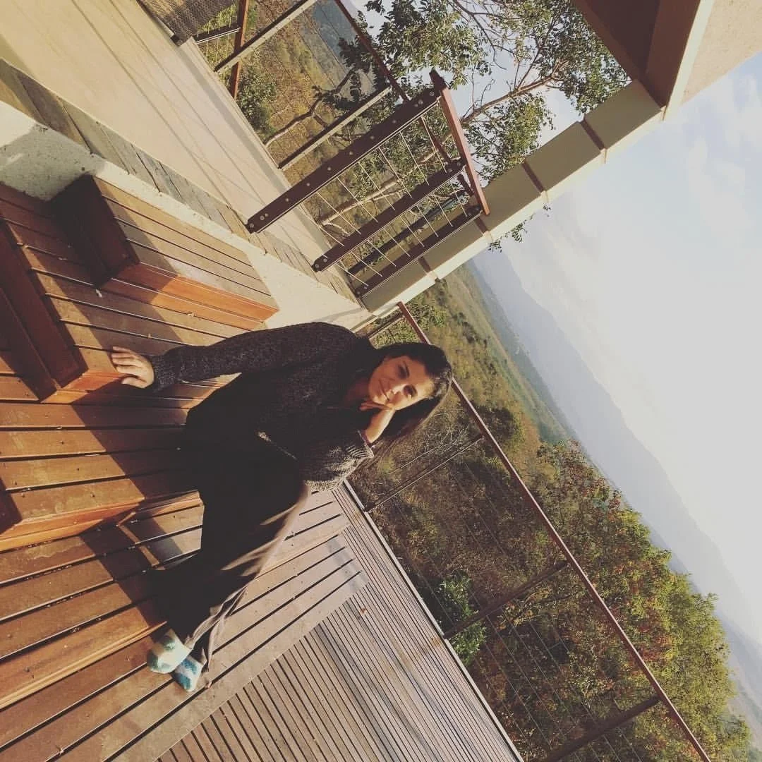 Woman sitting on wooden deck overlooking scenic landscape