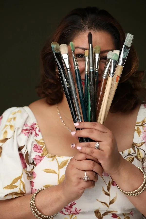 Een vrouw houdt een bos make-up penselen voor haar gezicht, met only haar ogen en haar hand zichtbaar.