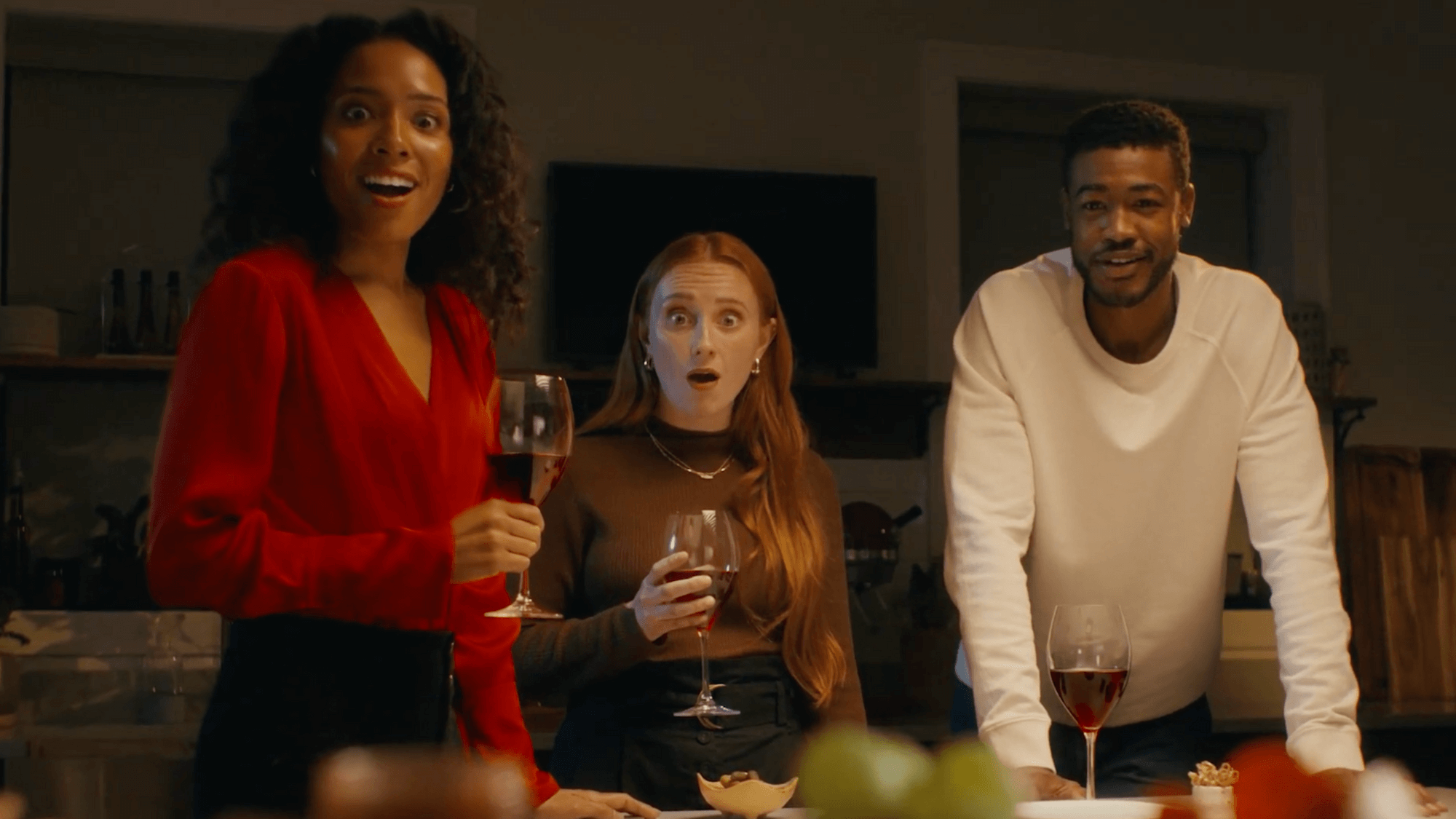 Three young people hold wine glasses and look directly at camera in surprise.