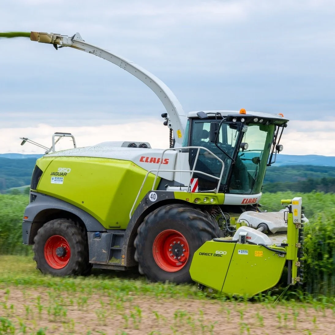 Moderne grüne Erntemaschine, Feldarbeit, blaue Himmel im Hintergrund, Marke Claas Jaguar.