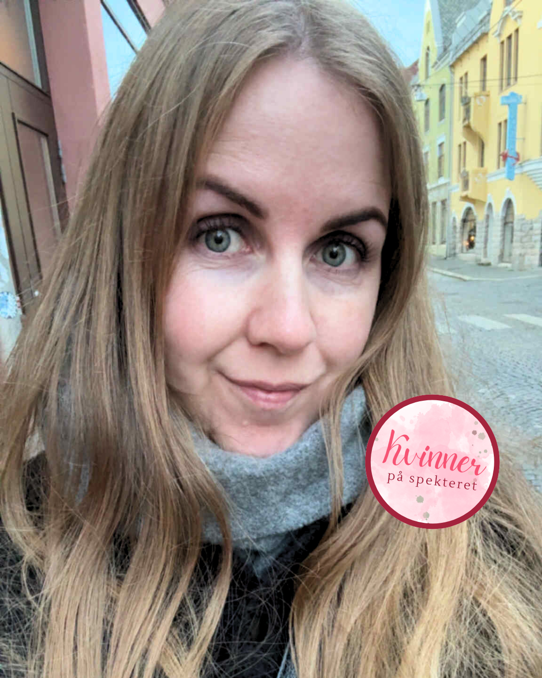 En kvinne  som smiler lurt, hun er ute. Det er en rosa ring hvor det står kvinner på spekteret. Dama har forstått seg selv og vil dele sin historie om hvordan det er å leve med AuDHD.