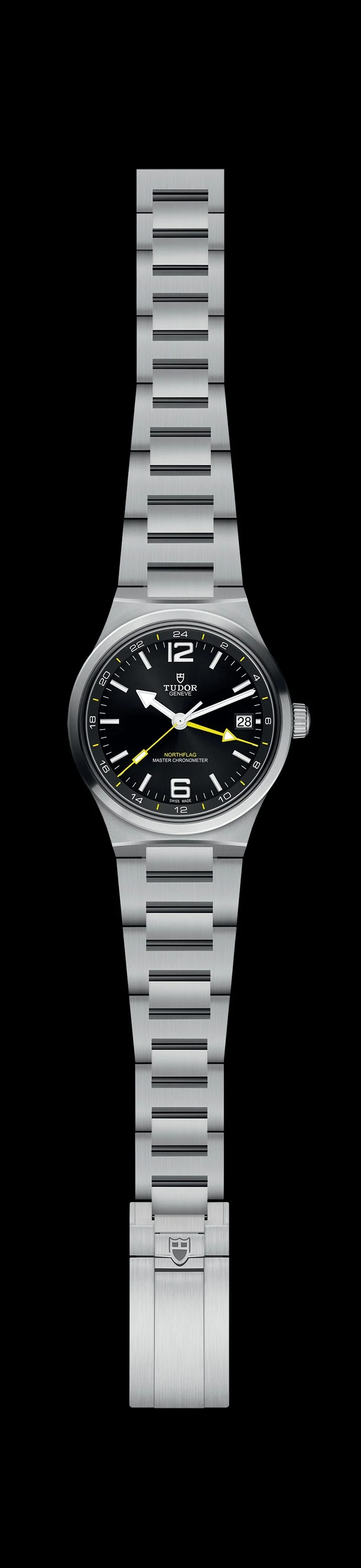Tudor North Flag GMT with black dial, yellow GMT hand and integrated two-link stainless steel bracelet against a black background.