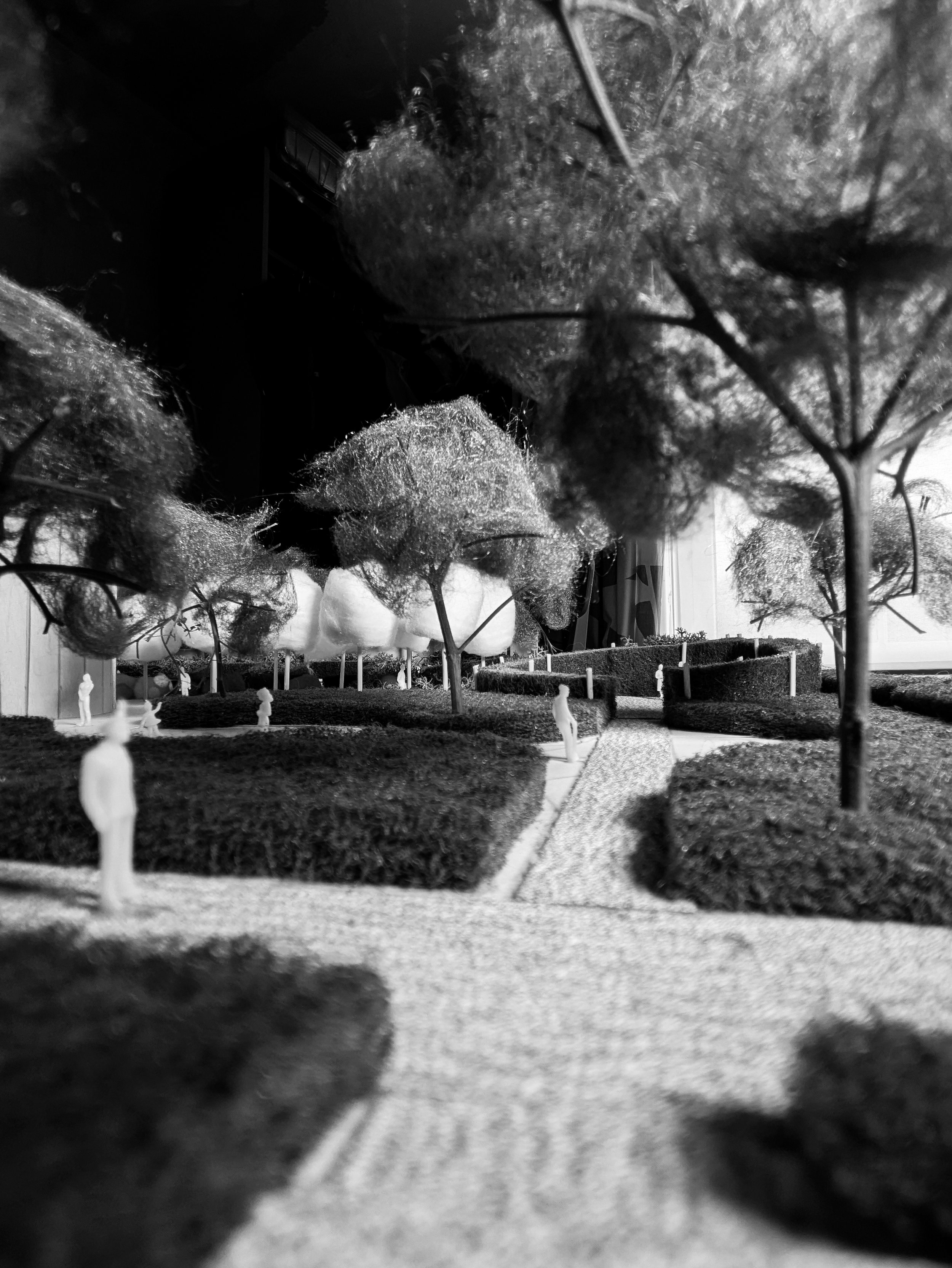Black and white photo of an architectural model showing a park or garden layout with miniature trees and small human figures.