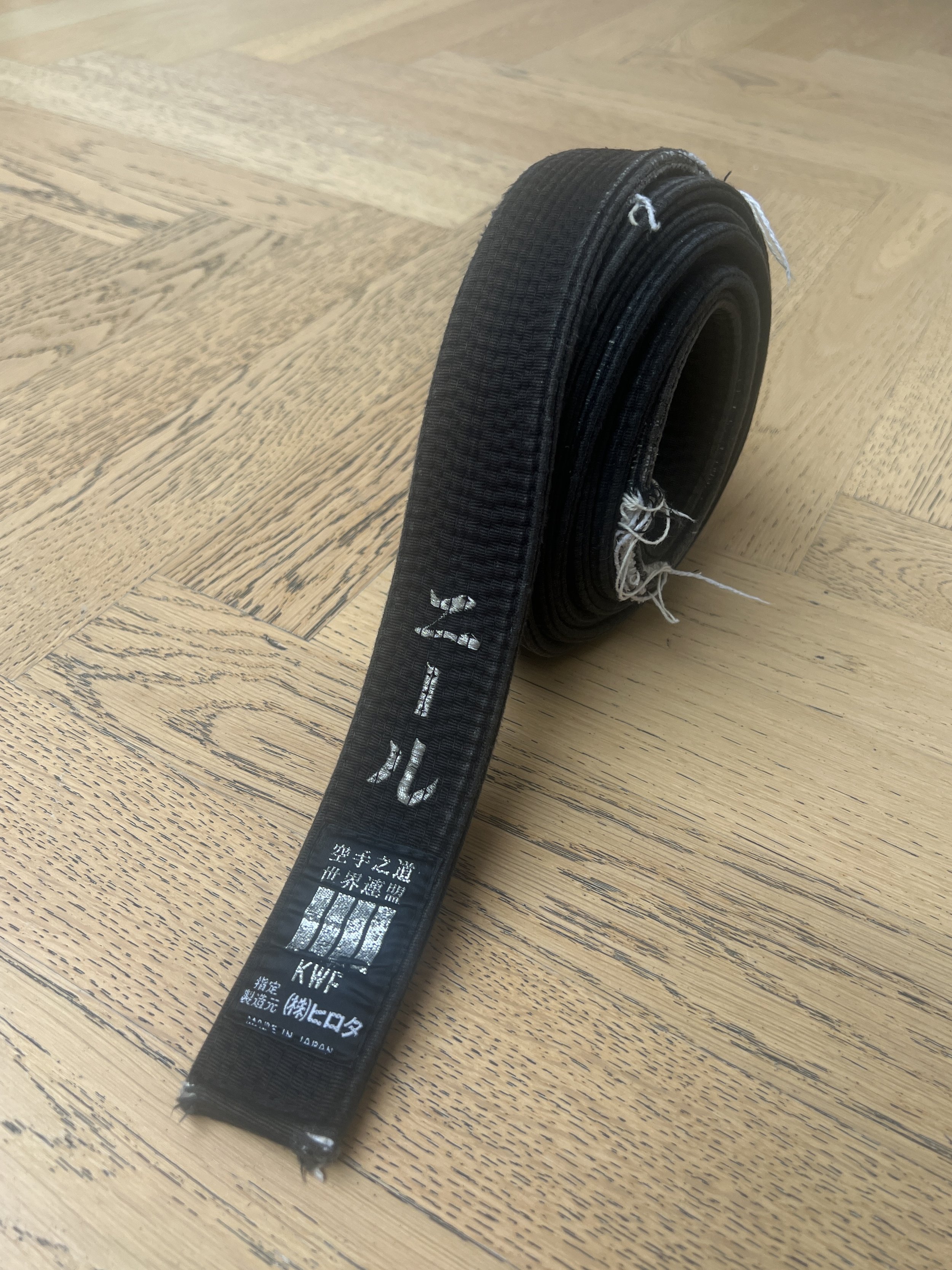 Rolled black martial arts belt on a wooden floor