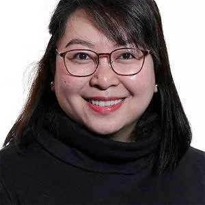 Portrett av en smilende kvinne med briller og mørkt hår, iført svart høyhalset genser.