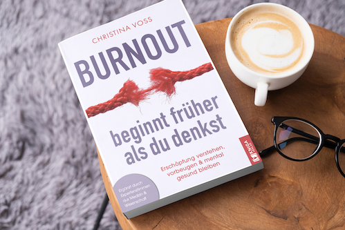 Christina Voss Burnout beginnt früher als du denkst Buch liegt auf einem Tisch neben einer Tasse Kaffe