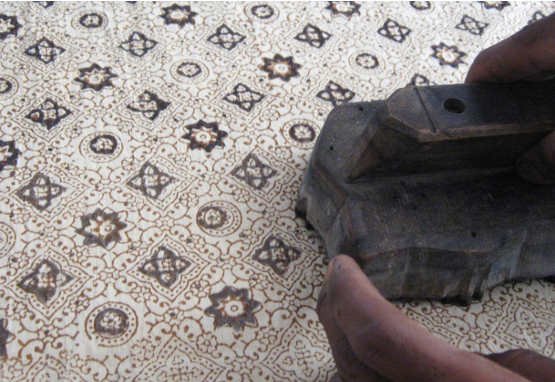 Person using a hand tool to carve a detailed pattern into the surface of a material.
