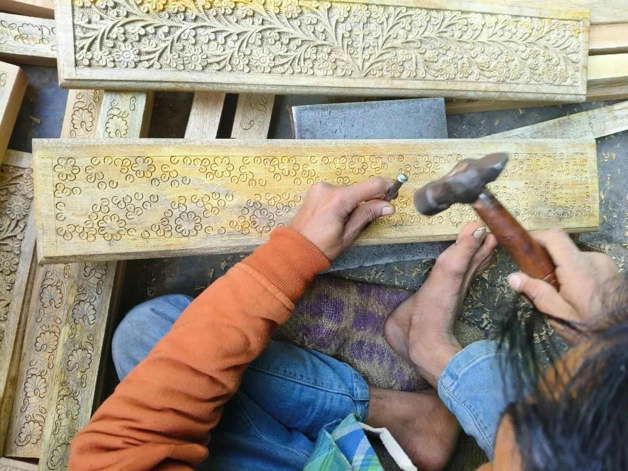 A craftsperson hand carving on mango wood