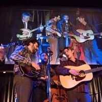 Bluegrass band performing on stage with projected image backdrop