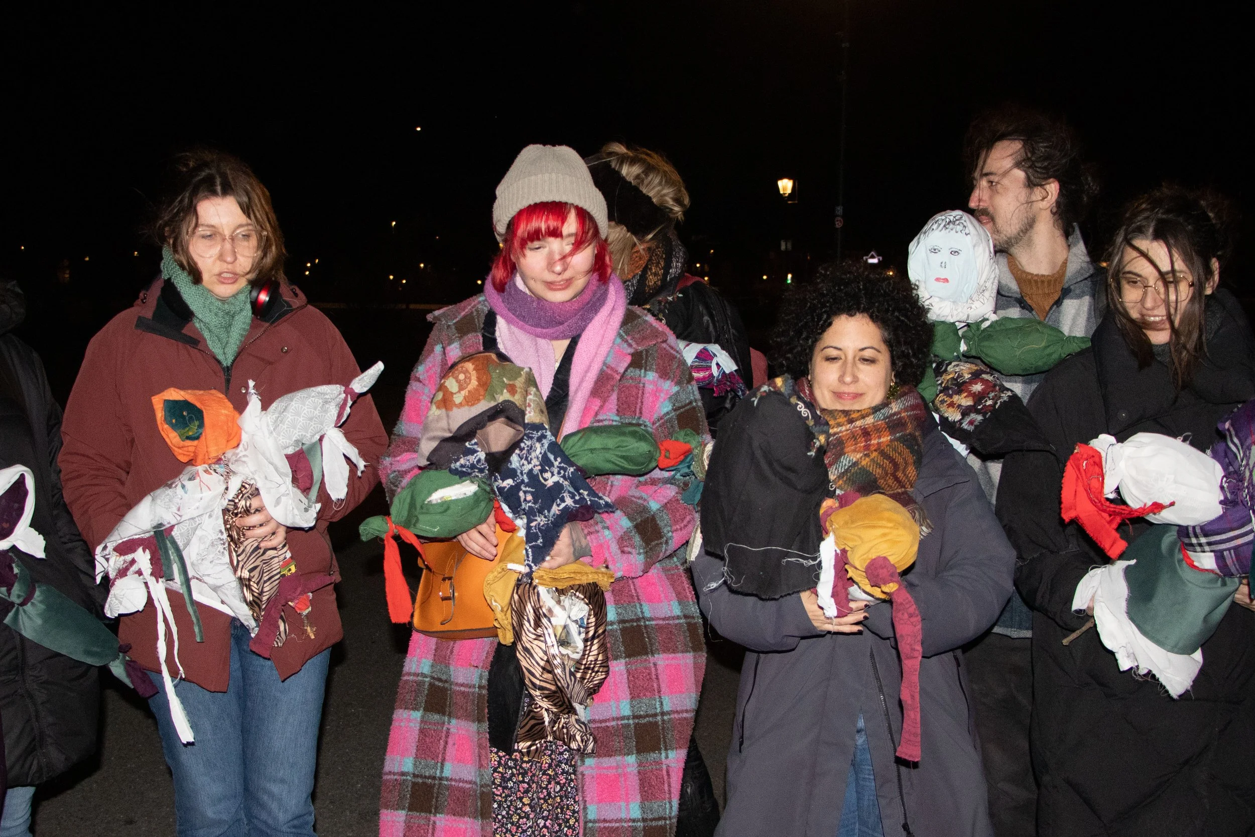Group of people holding handmade fabric Marzannas at night.
