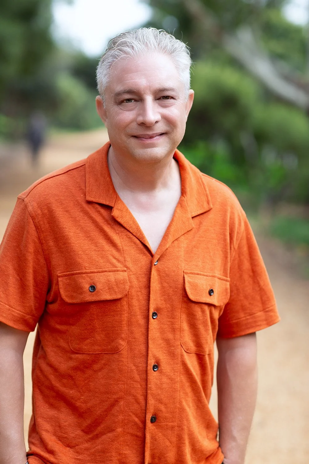 White older male EMDR therapist wearing an orange shirt and smiling