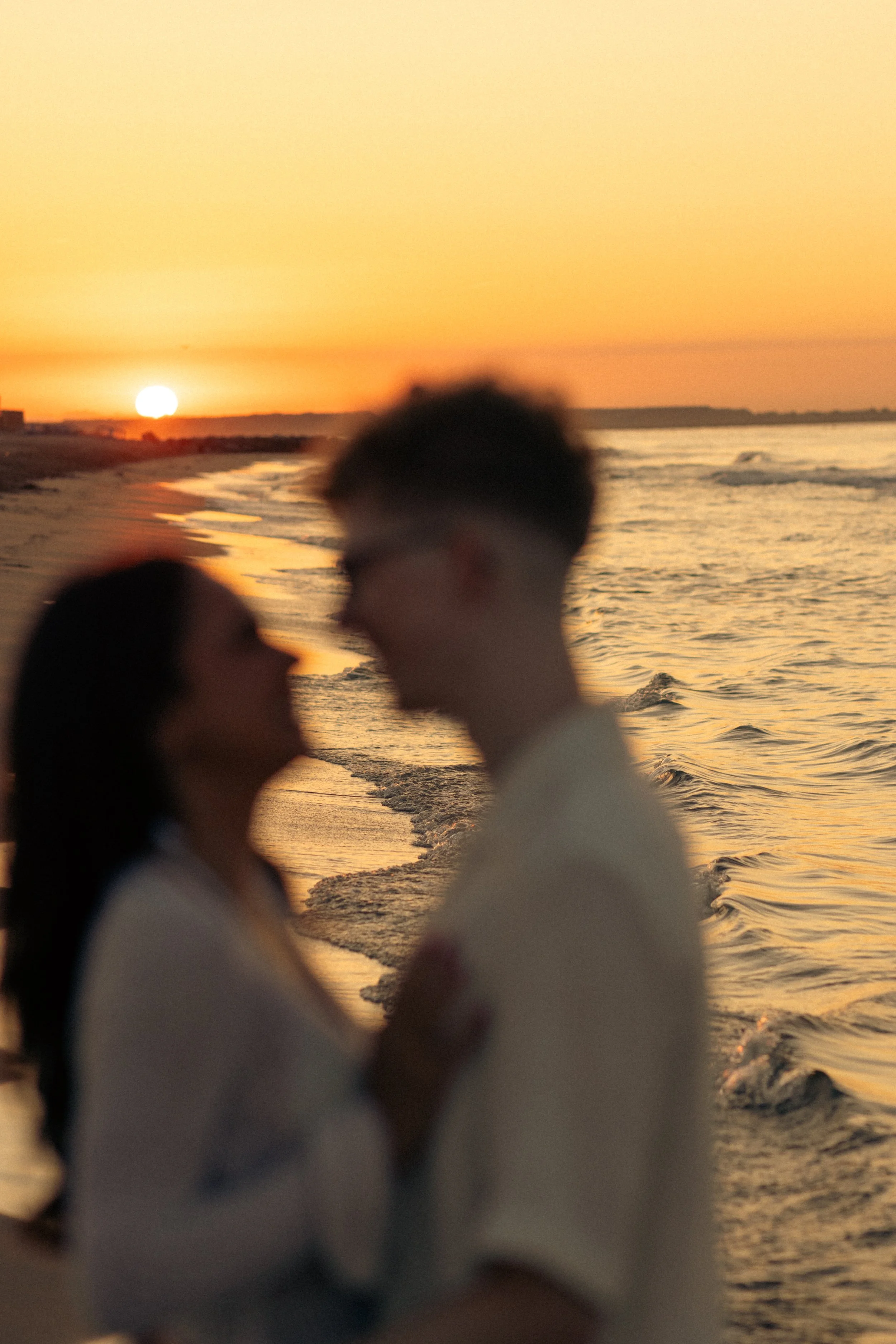 A blurry photo of a couple embracing on the beach during sunset.
