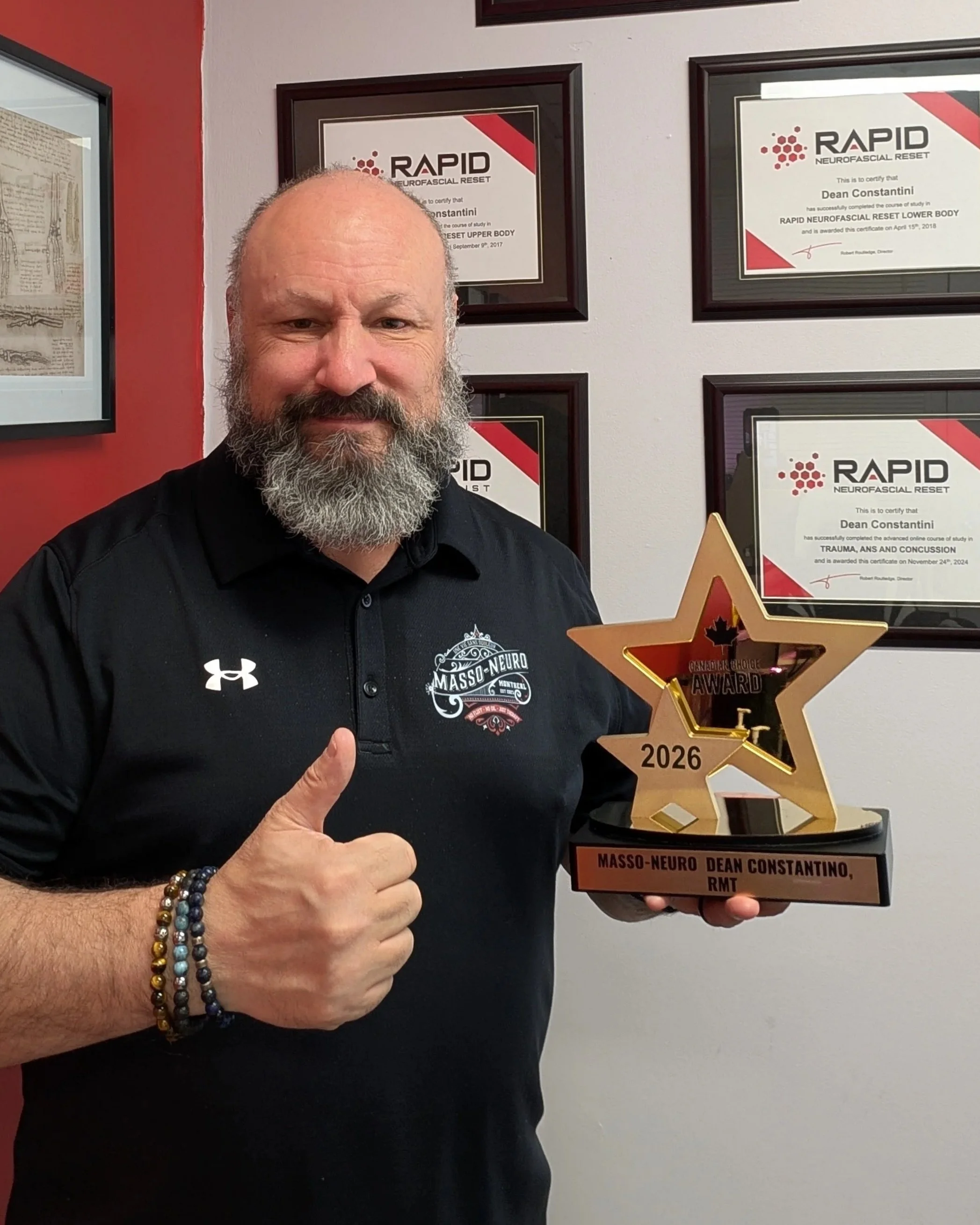 Dean Constantini, owner of Masso-Neuro and 2026 Canadian Choice Award winner for Best Massage Therapy in Longueuil, holding his award in his clinical office.