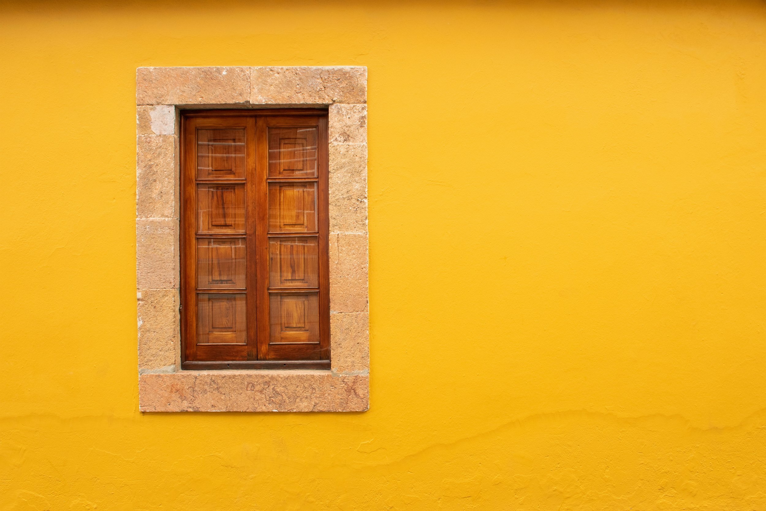 yellow wall stone building with window and wooden shutters