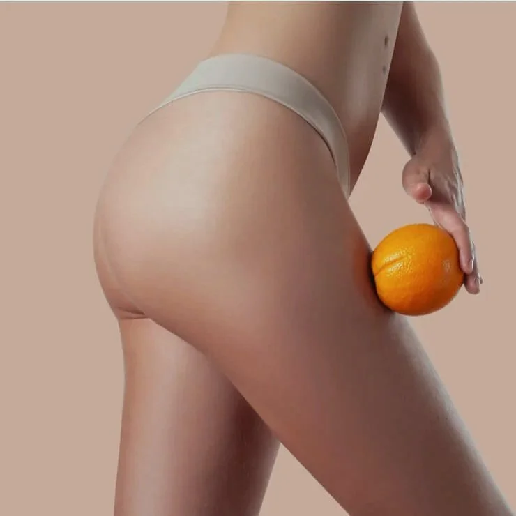 Femme en sous-vêtement tenant une orange contre sa cuisse.