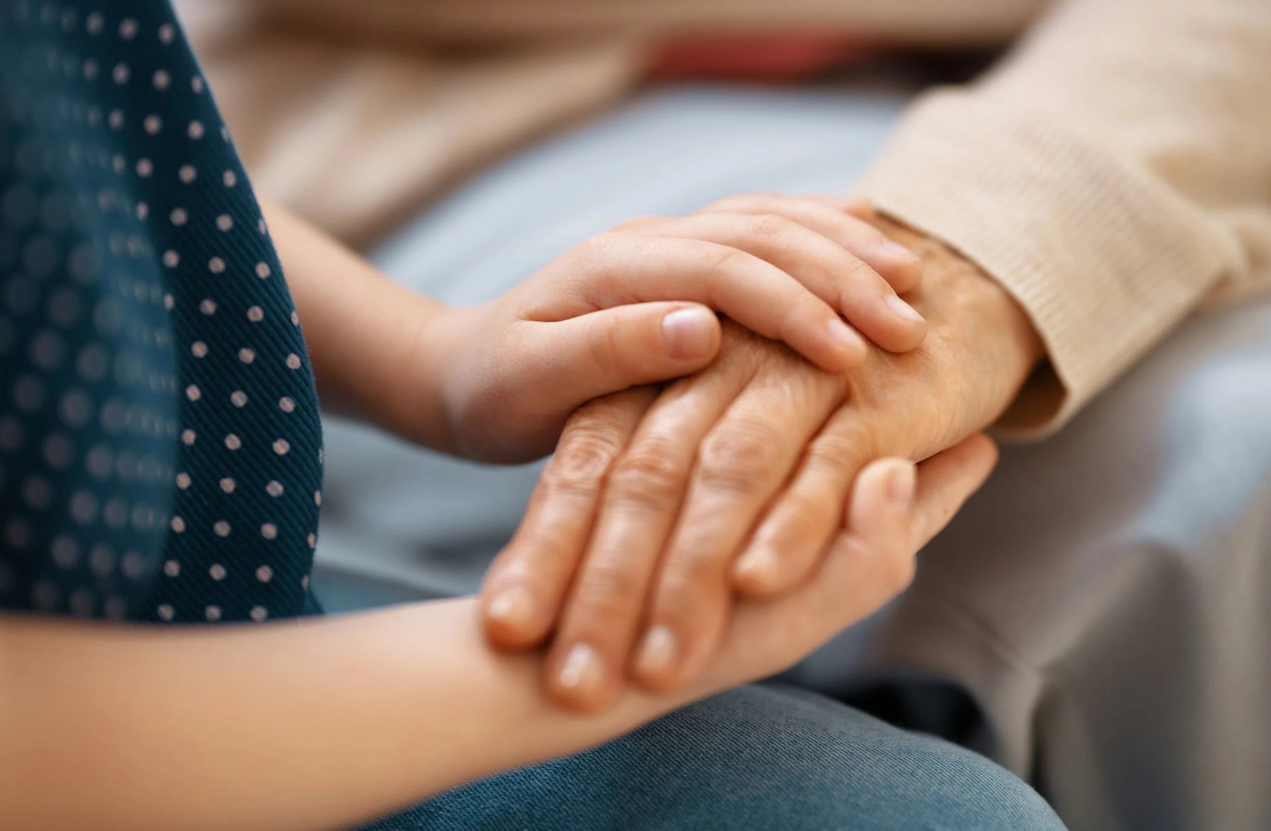 Child holding an elderly person's hand, illustrating comfort and support.